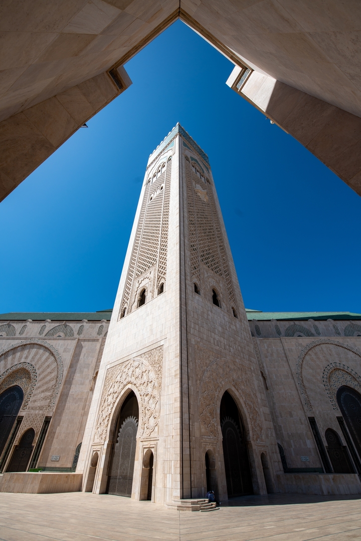 Un minaret imposant d'une mosquée se dressant contre un ciel bleu clair.