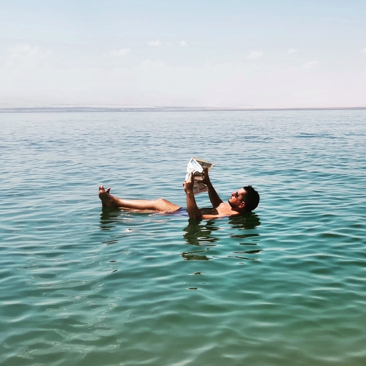 Homme flottant sur la mer Morte en lisant un journal.