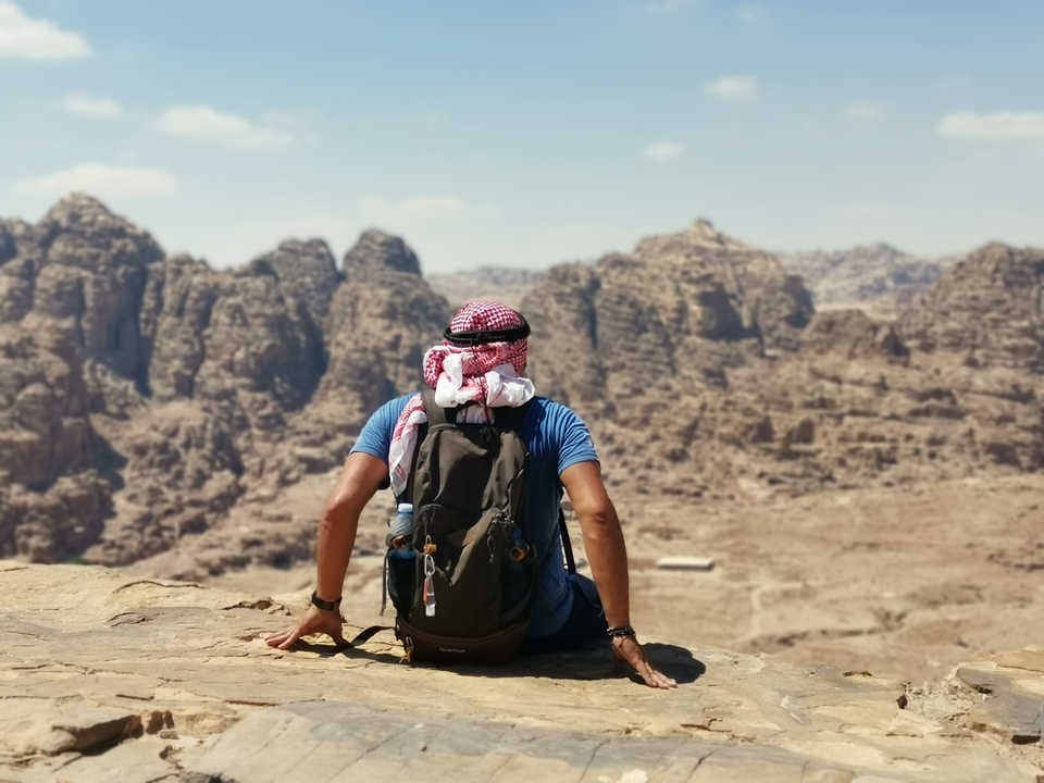 Personne assise sur un rocher, contemplant le paysage accidenté de Pétra.