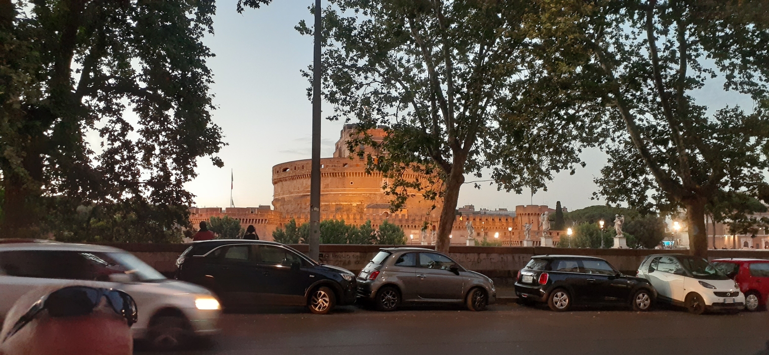 Vue du Castel Sant'Angelo à Rome le soir avec des voitures au premier plan.