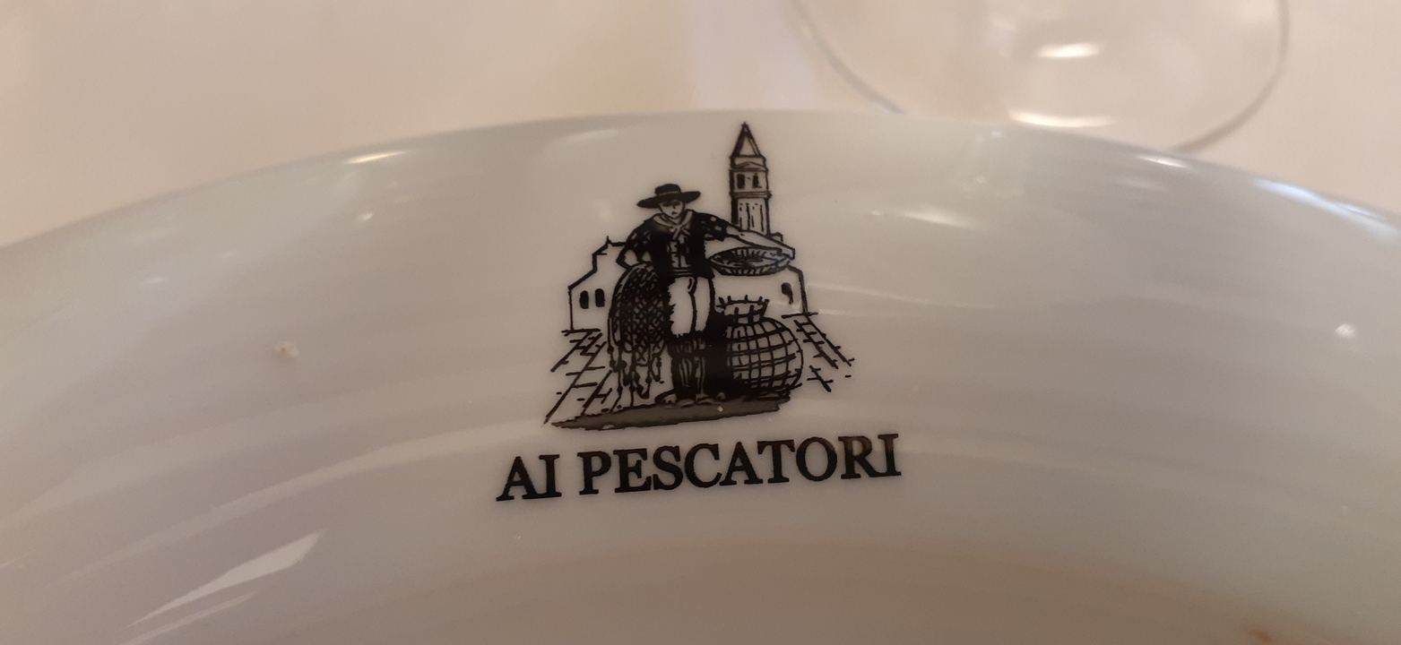 "Ai Pescatori" imprimé sur une assiette décorative dans un restaurant italien.
