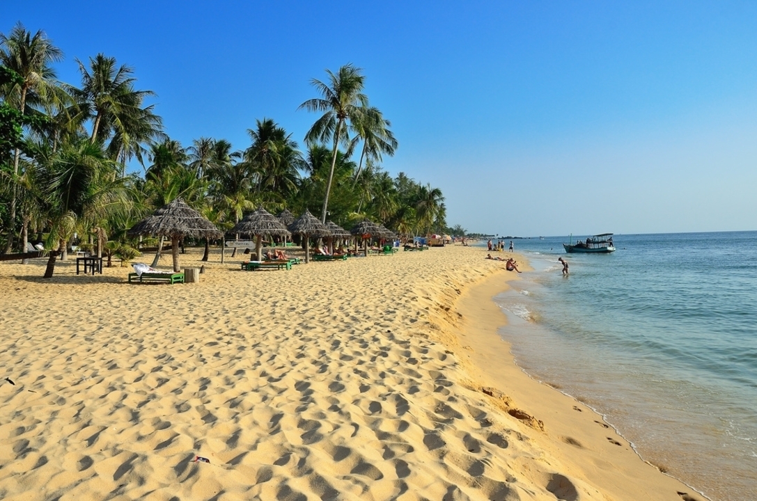 Plage de sable avec palmiers et touristes