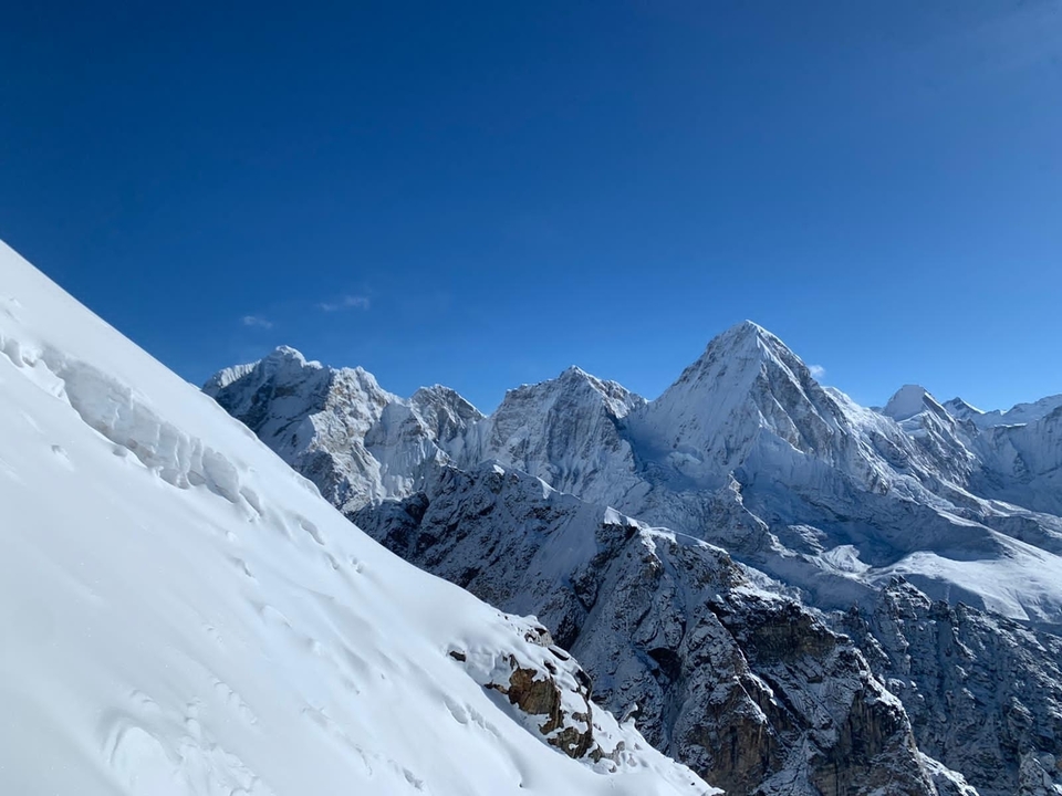 Pristine snow-covered Himalayan peaks under deep blue sky, seen from a high ridge