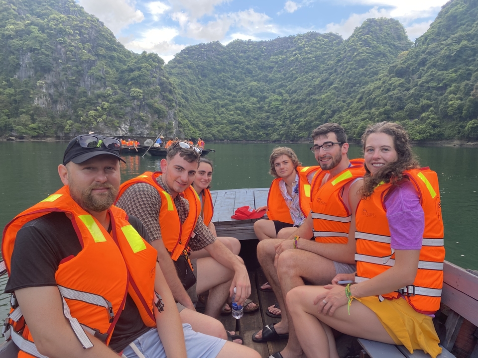 Des personnes en gilets de sauvetage sur un bateau avec des karsts calcaires en arrière-plan.