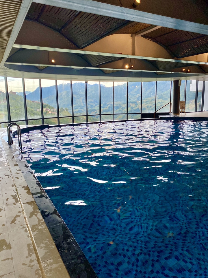 Piscine intérieure avec de grandes fenêtres donnant sur un paysage montagneux.