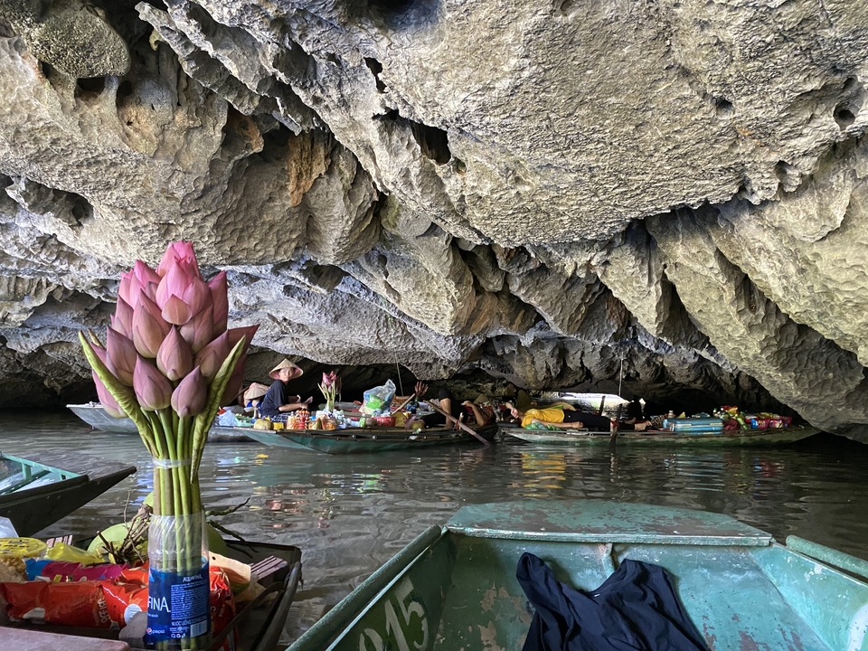 Des gens dans de petites embarcations flottant dans une grotte avec des stalactites.