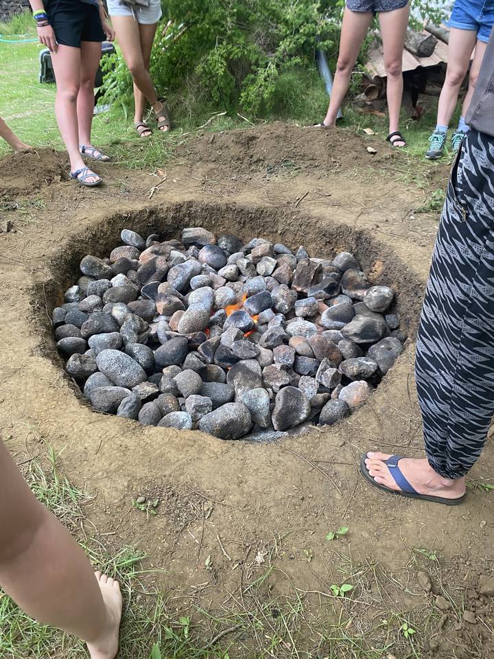 Des pierres disposées autour d'un feu dans une fosse peu profonde.