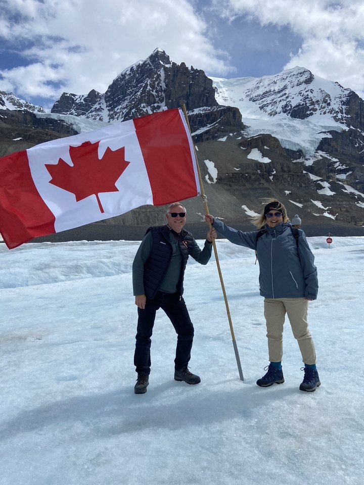 Deux personnes tenant un drapeau canadien sur la neige.