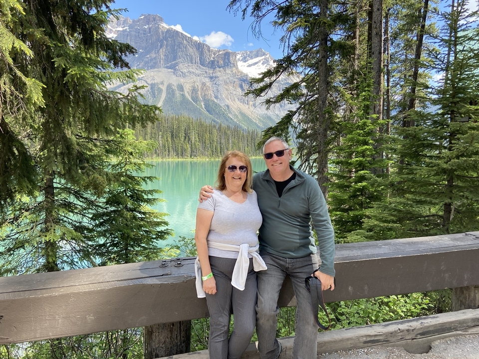 Couple posant près d'un lac turquoise entouré de montagnes.