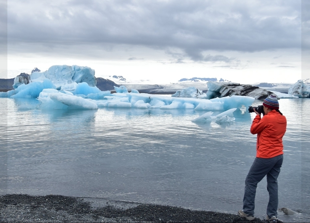 Personne photographiant des icebergs sur un lac glaciaire.