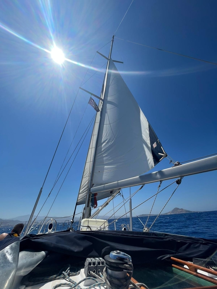 Voilier avec une voile partiellement déployée sous un ciel bleu dégagé.