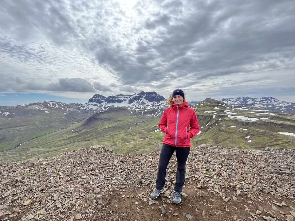 Personne qui prend la pose sur une montagne rocheuse avec des plaques de neige.