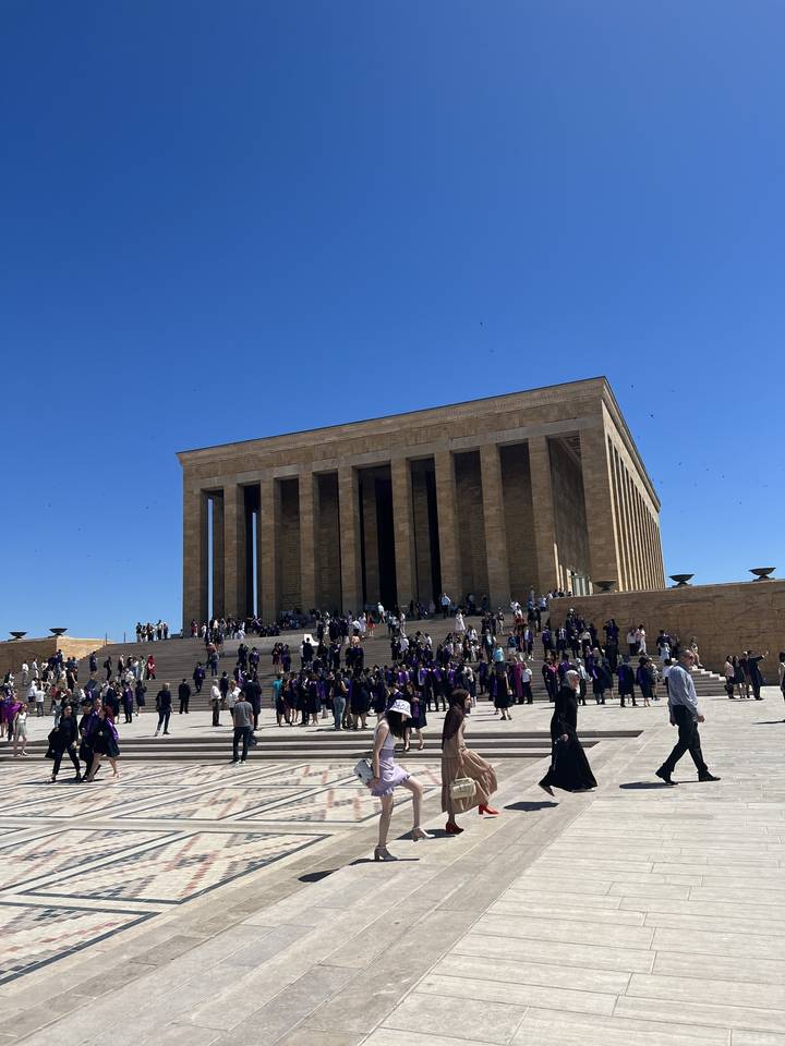 Grand bâtiment avec de nombreuses colonnes et des gens rassemblés à l'extérieur.