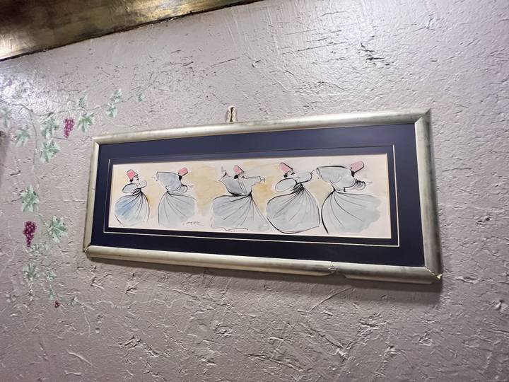 Art de derviches tourneurs dans un tableau encadré sur un mur.