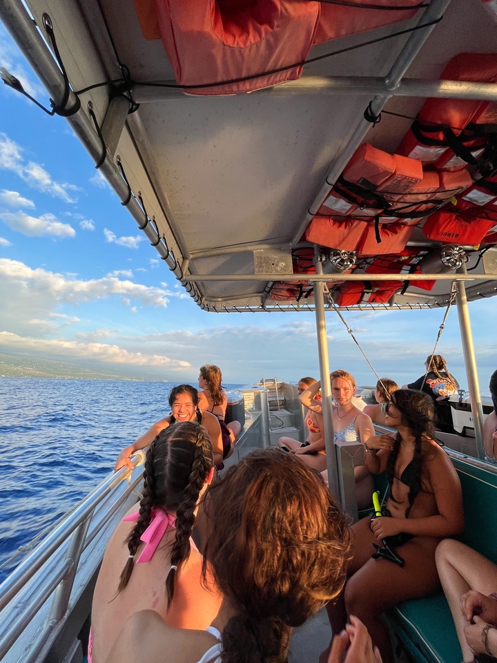 Des gens sur un bateau profitant d'une journée ensoleillée en mer avec la côte en arrière-plan.