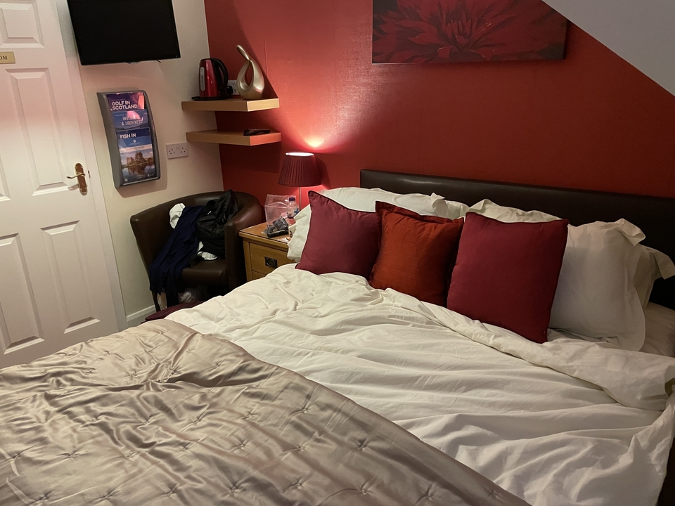 Intérieur d'une chambre douillette avec des oreillers rouges et une lampe sur une table de chevet.