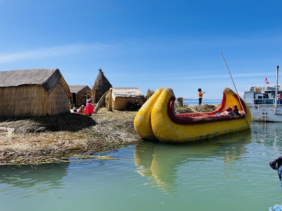 Bateaux traditionnels en roseau et huttes sur un lac.