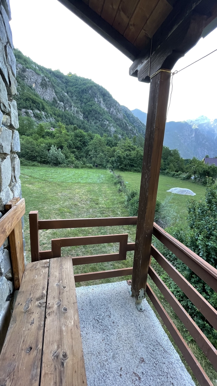 Wooden balcony overlooking a freshly mown grass field bordered by forest