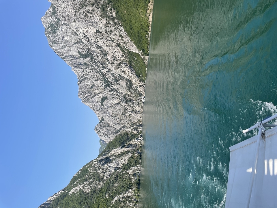 Boat cruising through a dramatic canyon with sheer limestone cliffs and emerald water
