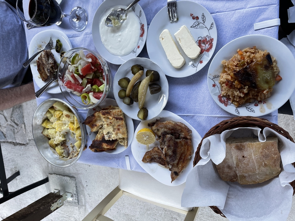 Hearty Albanian lunch spread featuring grilled meat, salads, pickles and fresh bread