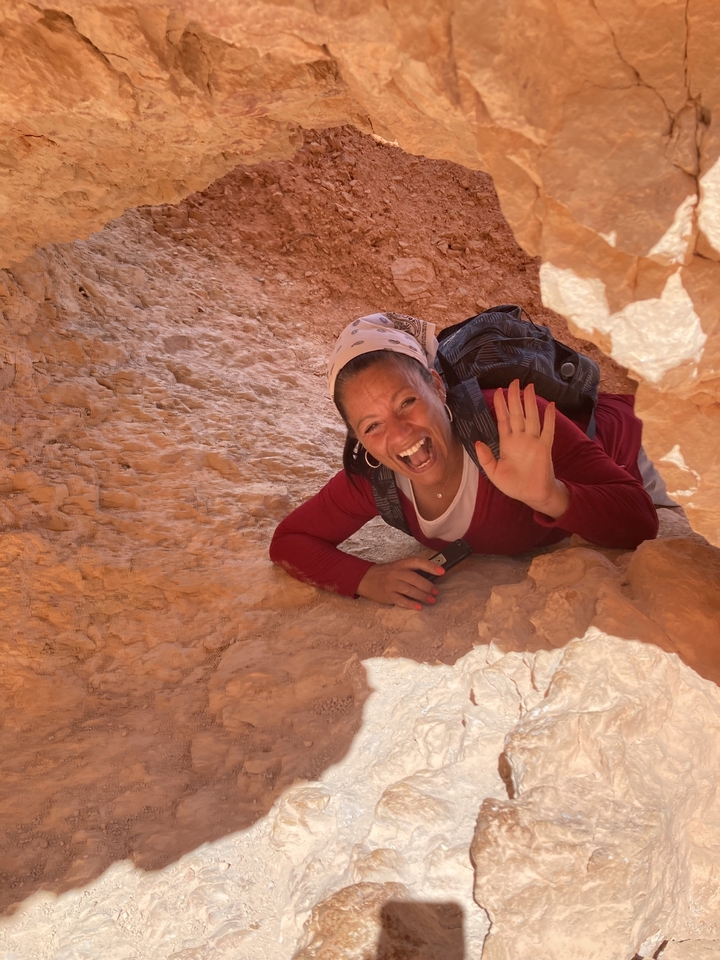 Femme qui fait signe de la main en explorant un terrain rocheux.