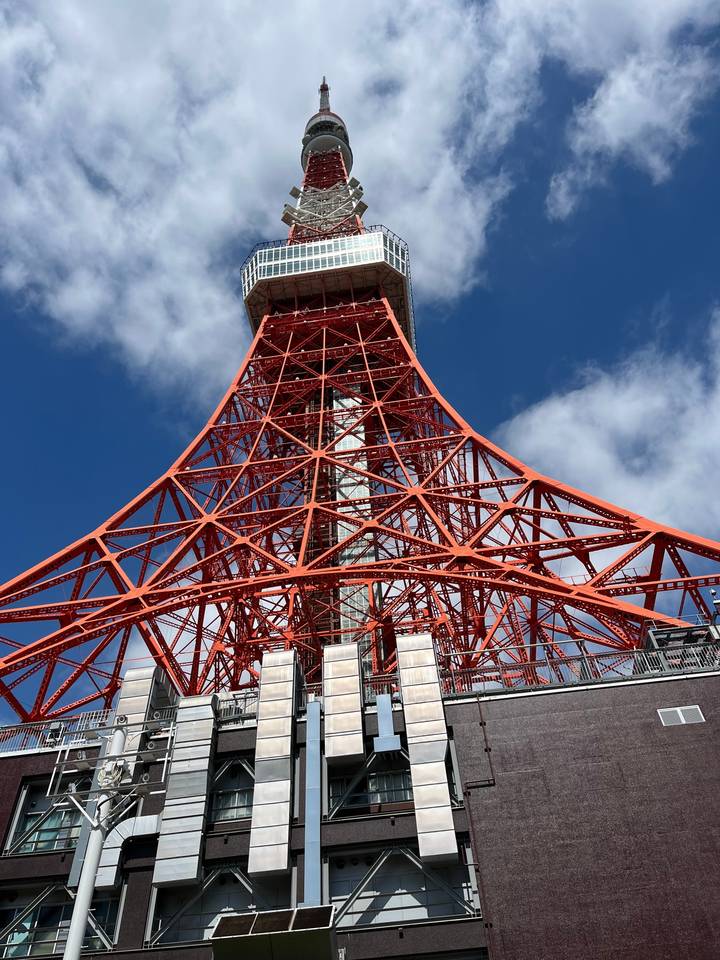 Une grande tour rouge contre le ciel, partiellement cachée par des bâtiments.