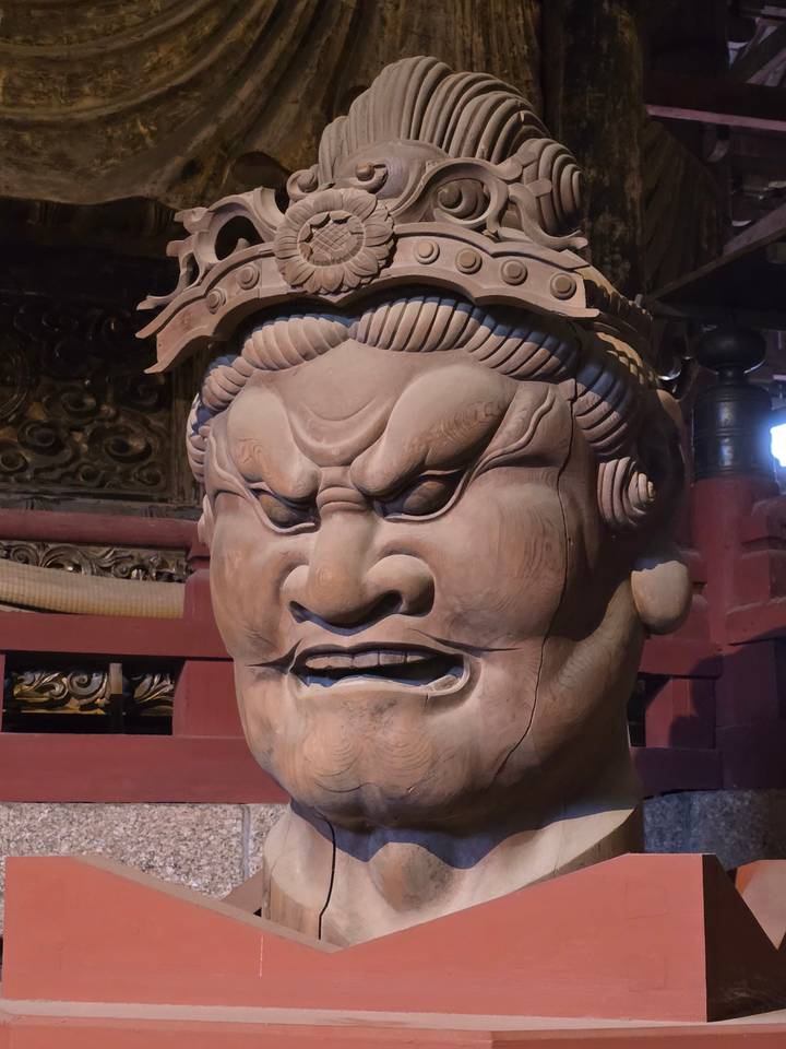 Grande tête sculptée en bois d'une divinité dans un temple.