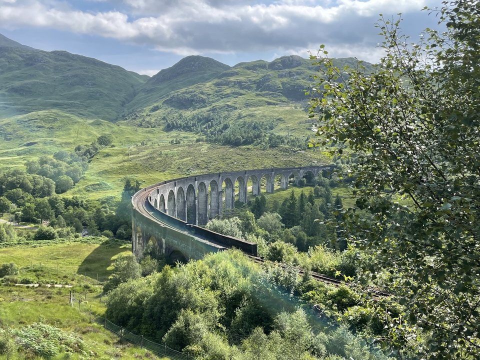Vue panoramique du viaduc de Glenfinnan entouré d'un paysage verdoyant luxuriant.