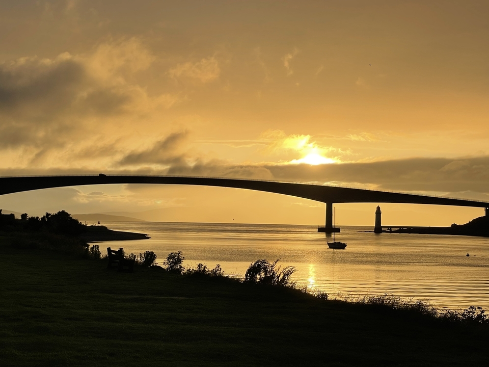 Vue imprenable sur le pont au coucher du soleil au-dessus d'une eau calme.