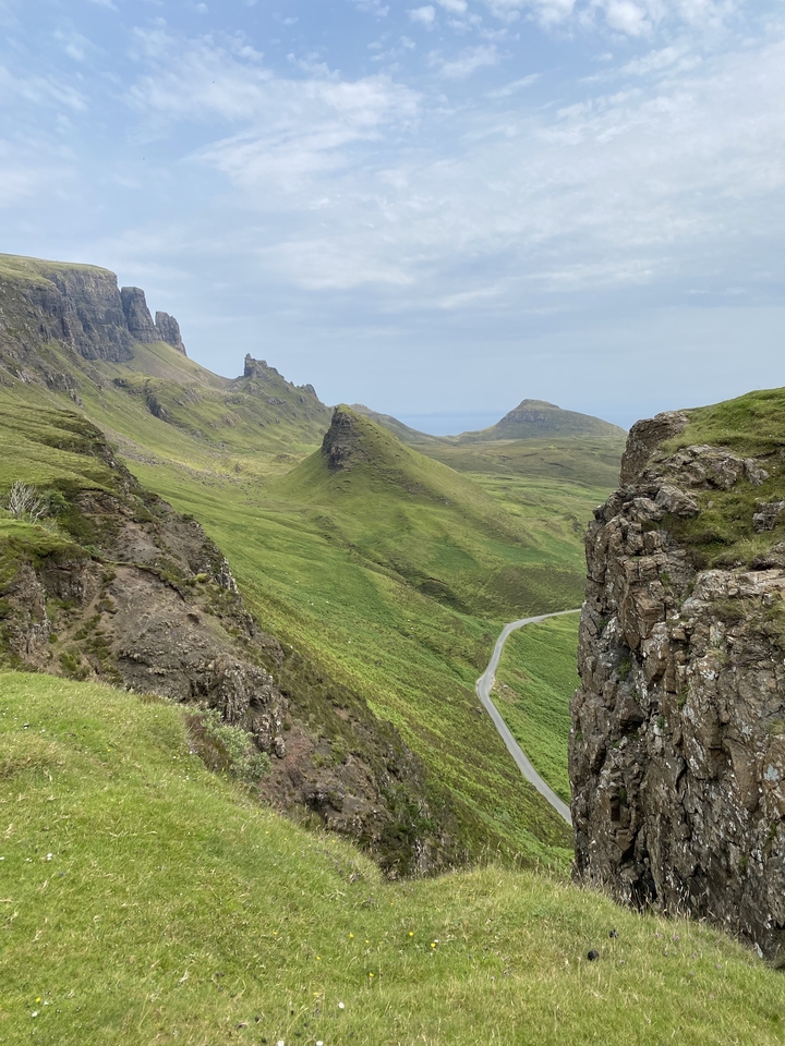 Collines et vallées majestueuses avec une route sinueuse.