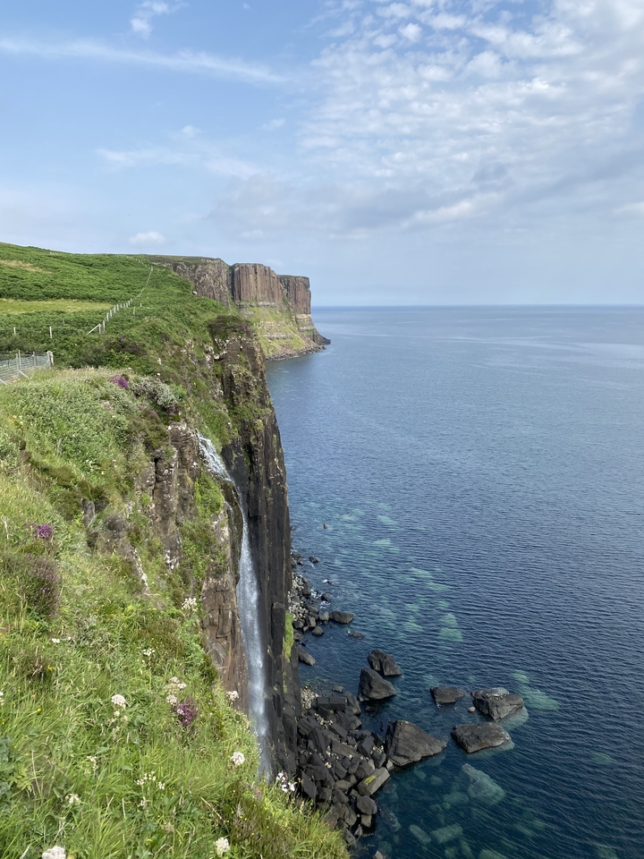 Des falaises avec une cascade qui se jette dans la mer.