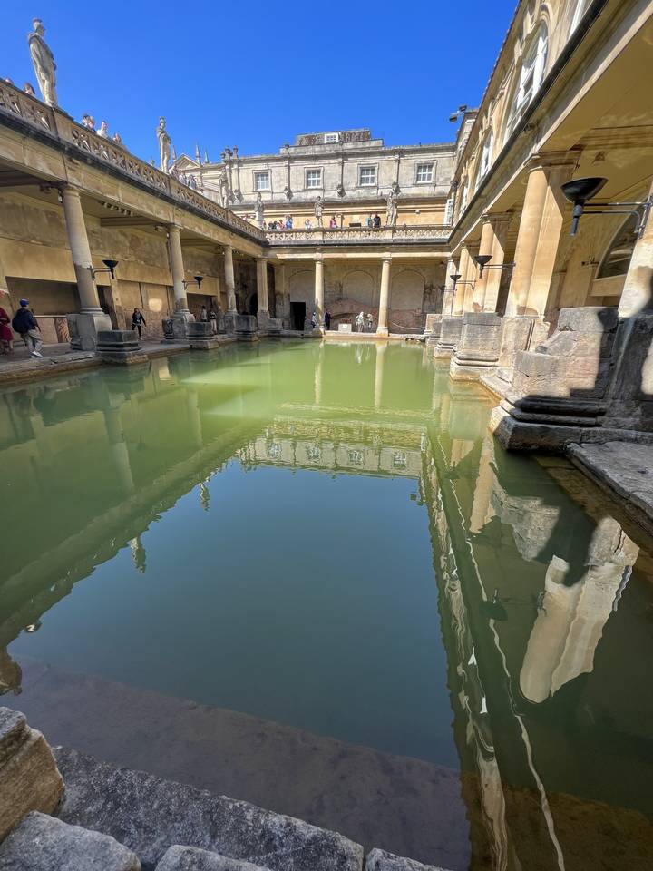 Thermes romains avec eau verte et architecture ornementée.