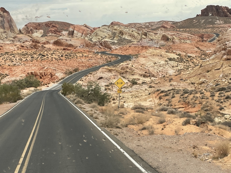 Route sinueuse à travers un paysage rocheux multicolore avec un panneau de déclivité.