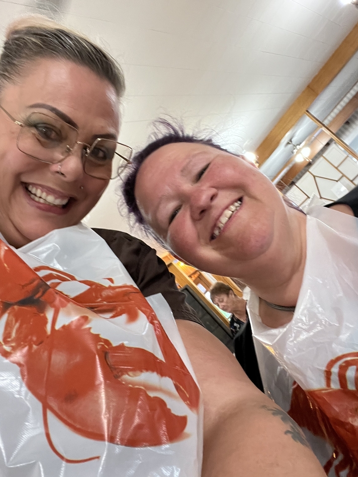 Deux femmes souriantes portant des bavoirs avec un motif de homard dans un restaurant.