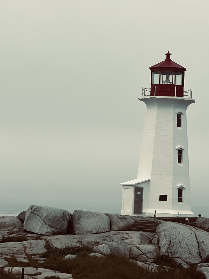 Grand phare avec un sommet rouge contre un ciel gris.