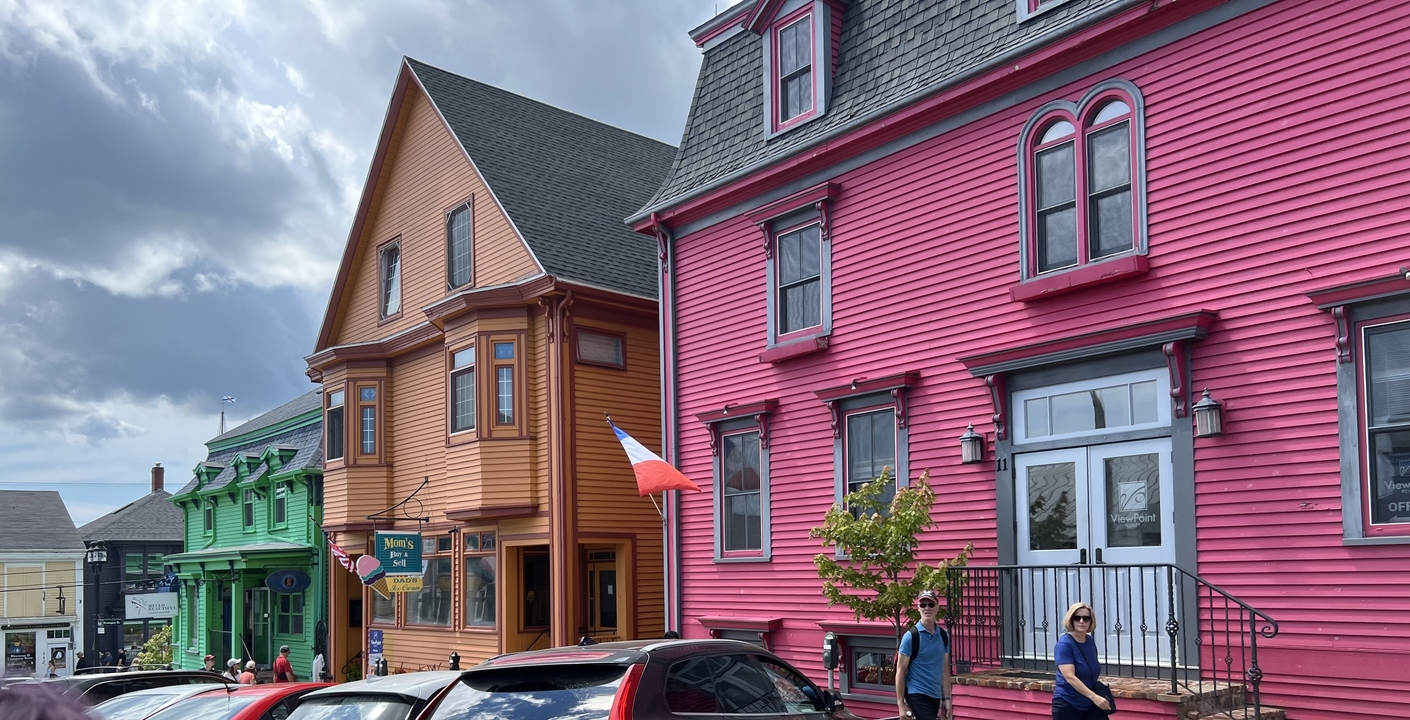 Maisons en bois aux couleurs vives dans une rue avec un drapeau.