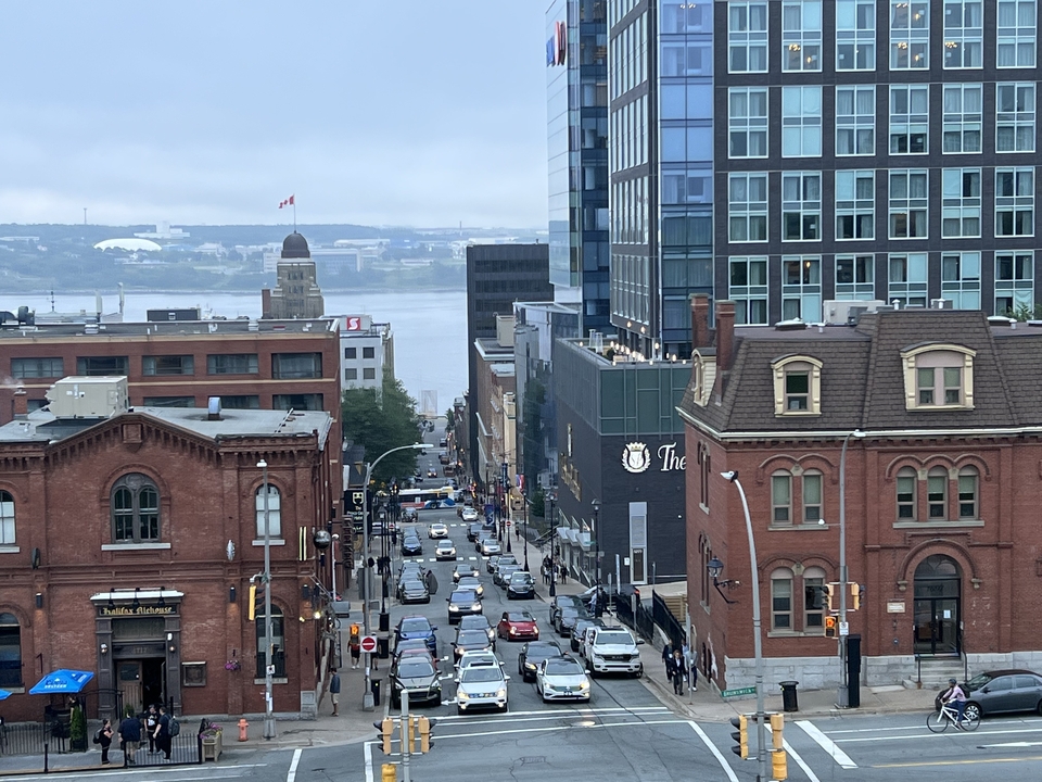 Vue d'une rue de ville avec des bâtiments historiques en brique rouge et un drapeau au loin.
