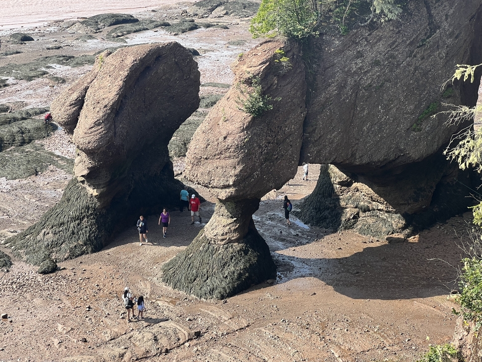 Des touristes explorant entre de grandes formations rocheuses à marée basse.