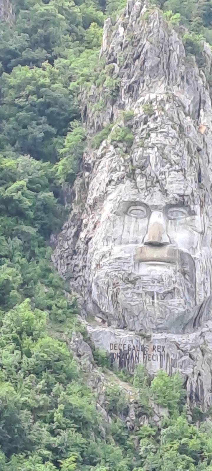 Une grande sculpture rupestre d'un visage dans le flanc de la montagne.