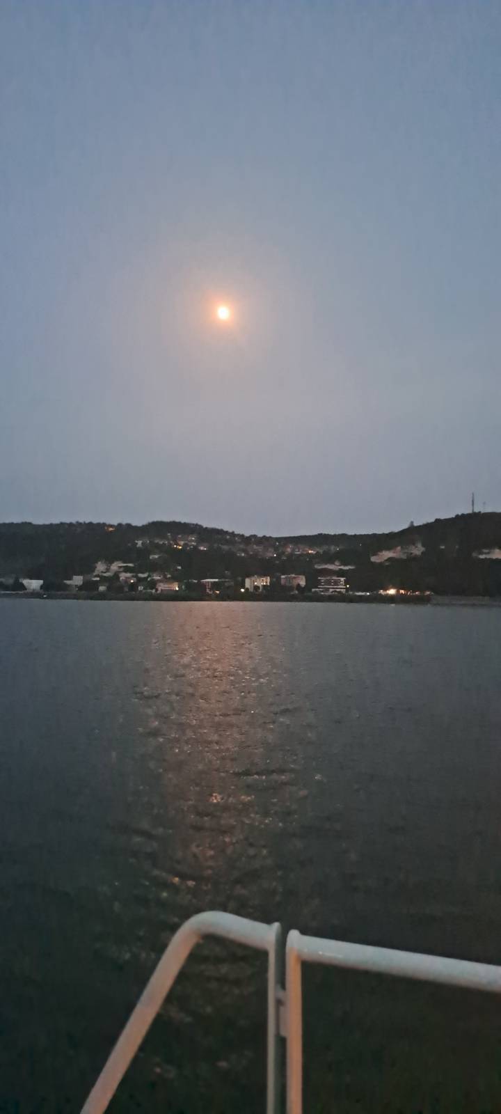 Une vue nocturne d'une ville de l'autre côté d'une rivière avec le clair de lune se reflétant sur l'eau.