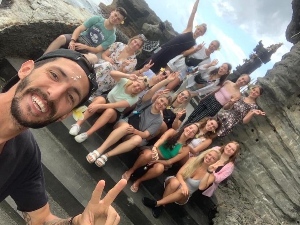 Groupe de personnes assises sur des escaliers souriantes et posant.