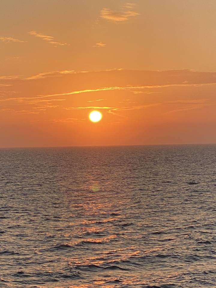 Coucher de soleil sur l'océan avec un reflet orangé sur l'eau.