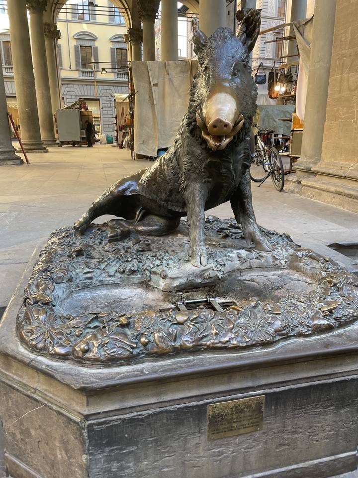 Une statue de sanglier en bronze dans un cadre urbain.