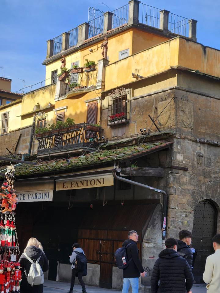 Façade d'immeuble colorée avec des balcons et des gens qui passent.