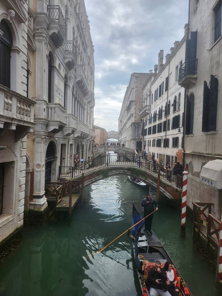 Gondole naviguant dans un canal étroit entre des bâtiments historiques.