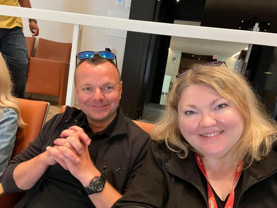 Deux personnes assises à l'intérieur en train de sourire.