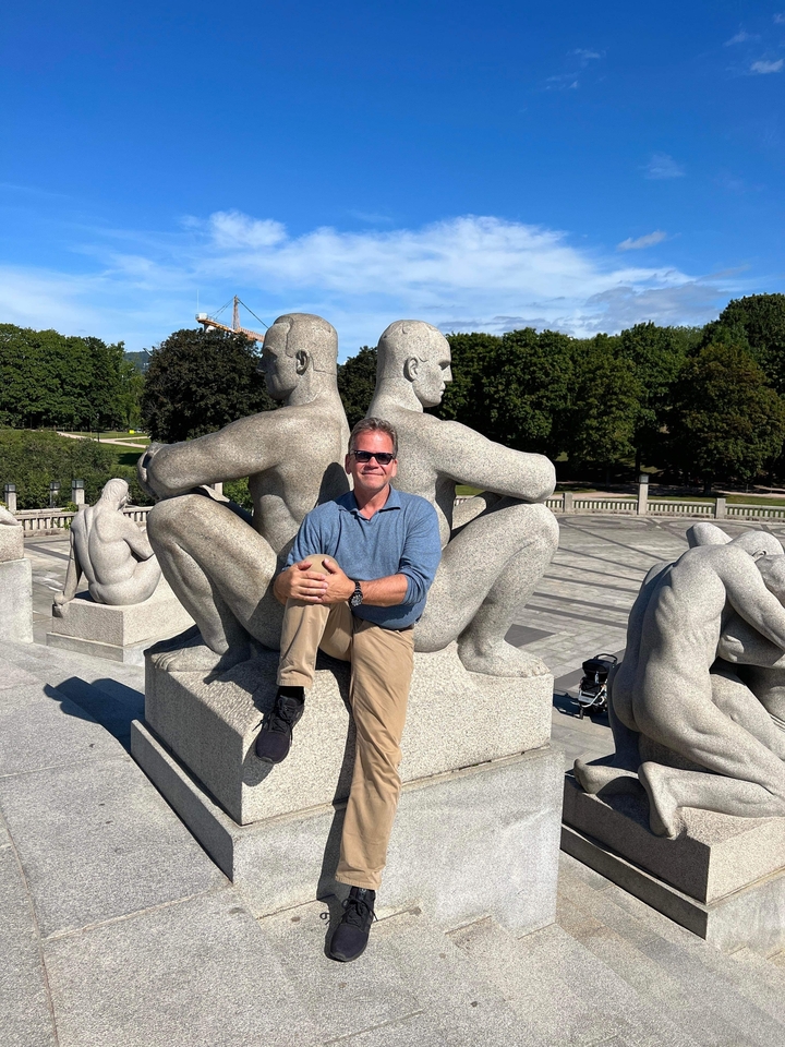 Homme assis sur une sculpture dans un parc.