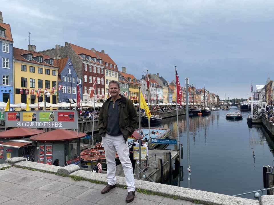 Homme debout sur le front de mer de Nyhavn avec des bâtiments colorés.