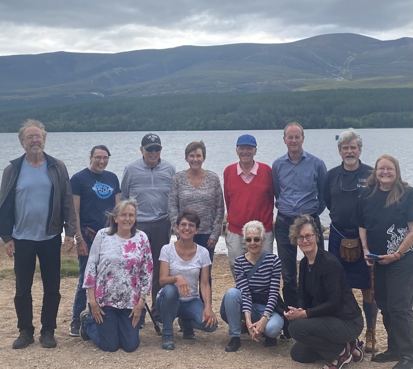 Un groupe de personnes posant près d'un lac avec des montagnes en arrière-plan.