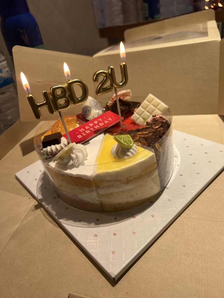 Un gâteau d'anniversaire avec diverses décorations incluant le texte « Joyeux Anniversaire ».